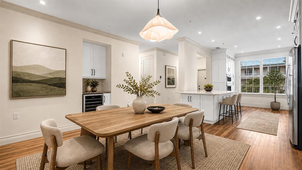 A dining area with a wooden table and chairs sits adjacent to a white kitchen — 4286 ANISSA AVENUE UNIT 10-202, ORLANDO, FL