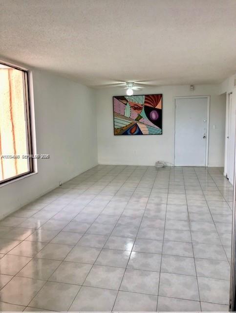 An empty room with white walls, light-colored tile flooring, a ceiling fan, and abstract wall art — 2000 Biarritz Dr # 407, Miami Beach FL 33141, MIAMI BEACH, FL