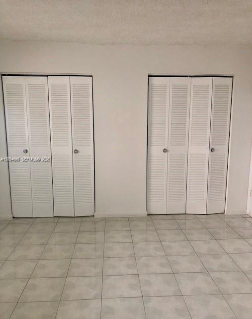 A room with light-colored tile flooring and two sets of white louvered closet doors — 2000 Biarritz Dr # 407, Miami Beach FL 33141, MIAMI BEACH, FL