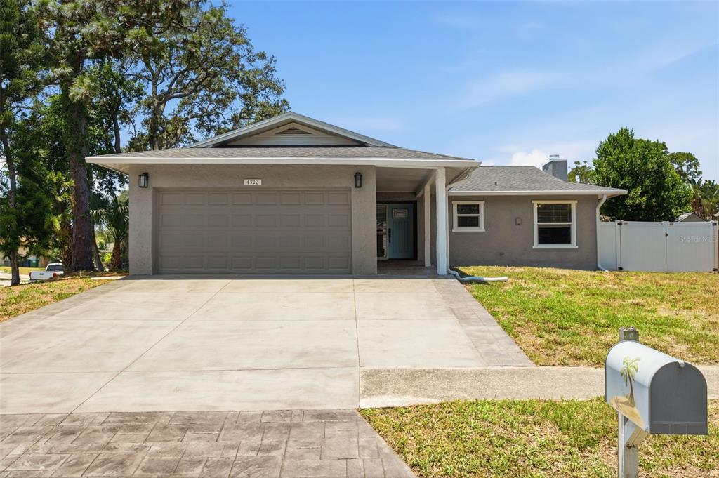 A single-story house with a gray exterior, a two-car garage, and a concrete driveway — 4712 SIMCOE STREET, PALM HARBOR, FL