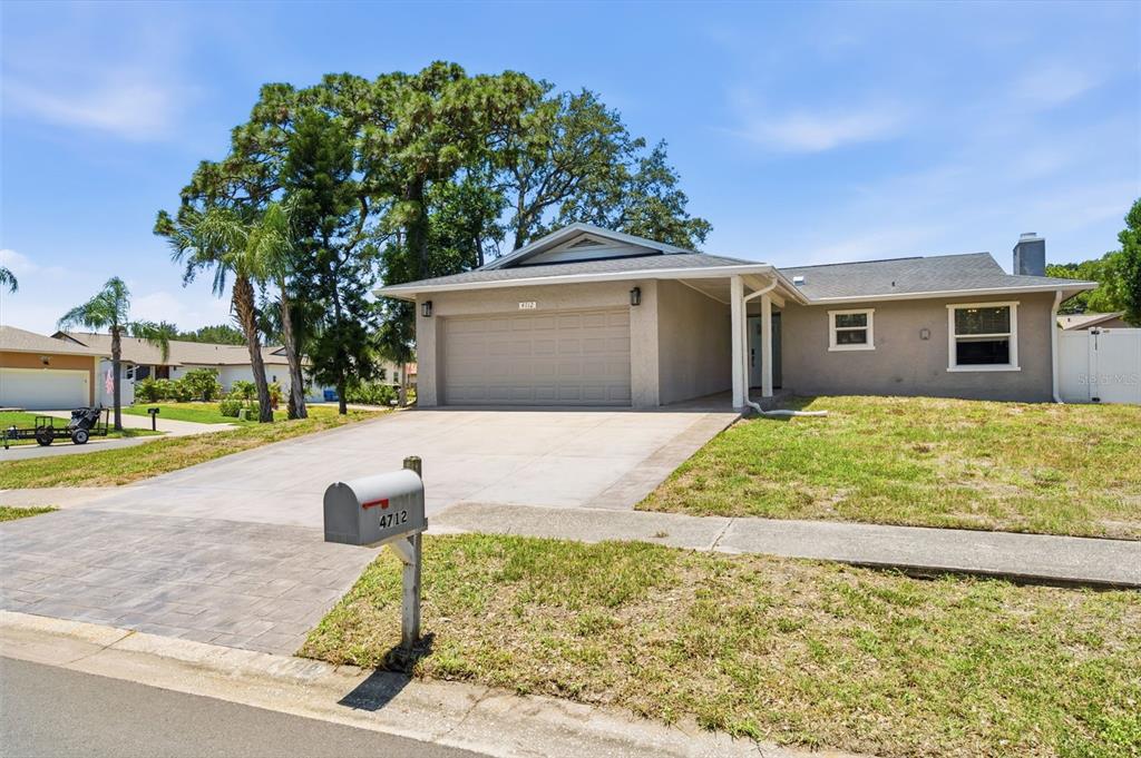 A single-story house with a two-car garage, a paved driveway, and a front lawn — 4712 SIMCOE STREET, PALM HARBOR, FL