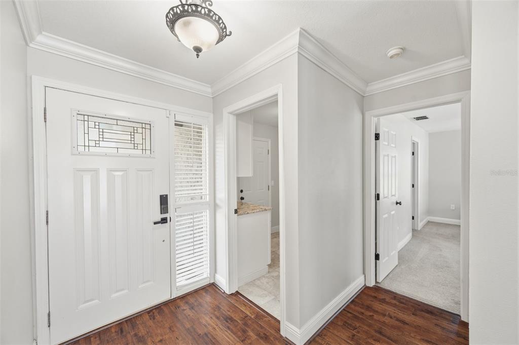An entryway features a white front door, wood-look flooring, and doorways leading to other rooms — 4712 SIMCOE STREET, PALM HARBOR, FL
