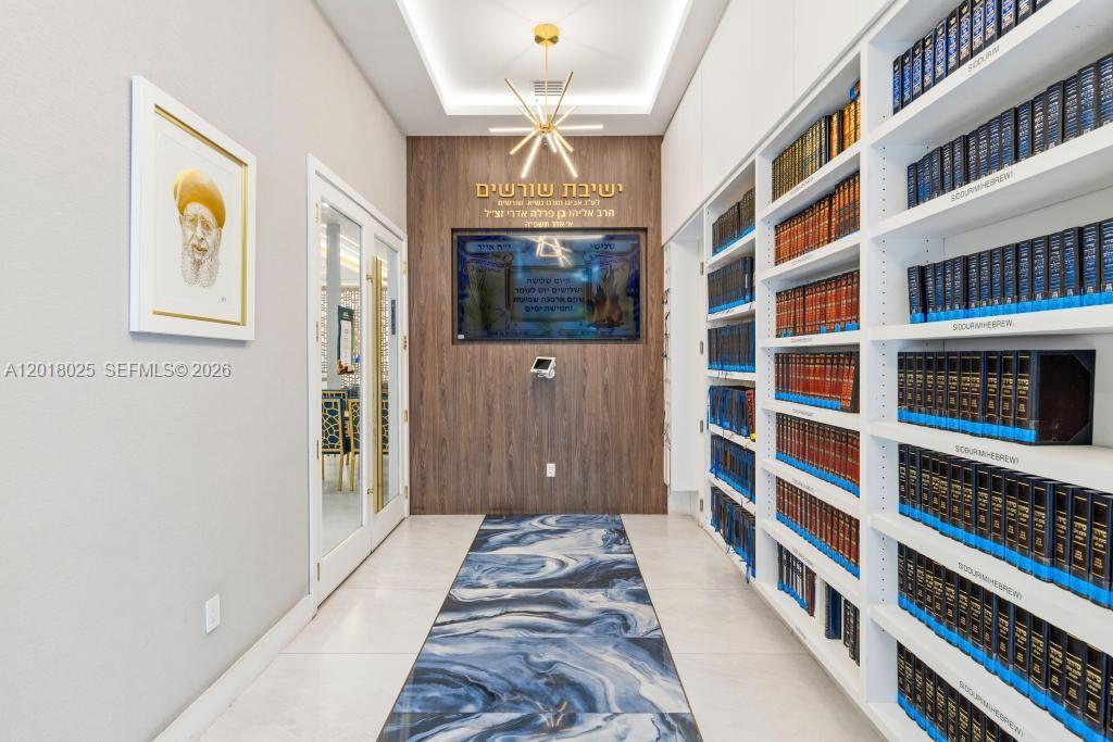 A hallway features a blue marble runner, white bookshelves filled with books, and a digital display — 5940 SW 37th Ave, Dania Beach FL 33312, DANIA BEACH, FL