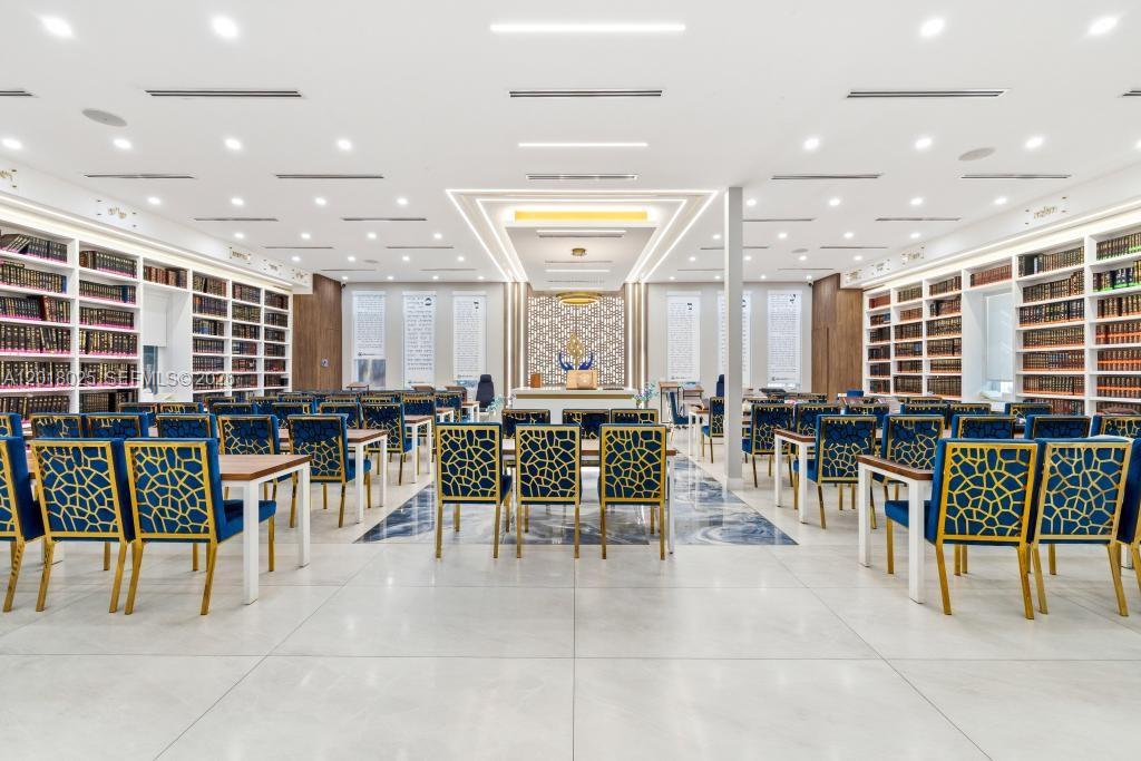 A large, modern study hall features rows of tables, blue patterned chairs, and extensive bookshelves — 5940 SW 37th Ave, Dania Beach FL 33312, DANIA BEACH, FL
