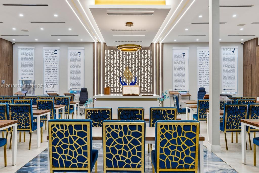 A modern synagogue interior features rows of blue patterned chairs facing a central bimah — 5940 SW 37th Ave, Dania Beach FL 33312, DANIA BEACH, FL
