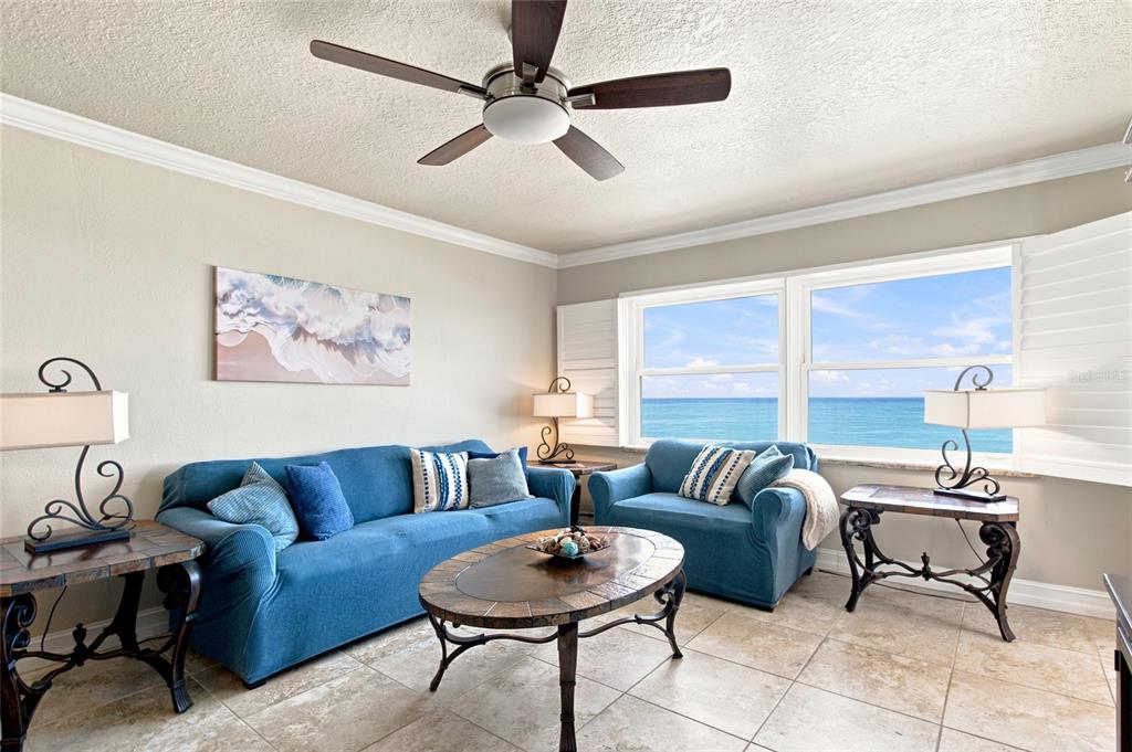 A living room features blue sofas, a tile floor, and a view of the ocean — 1270 GULF BOULEVARD UNIT 2007, CLEARWATER BEACH, FL