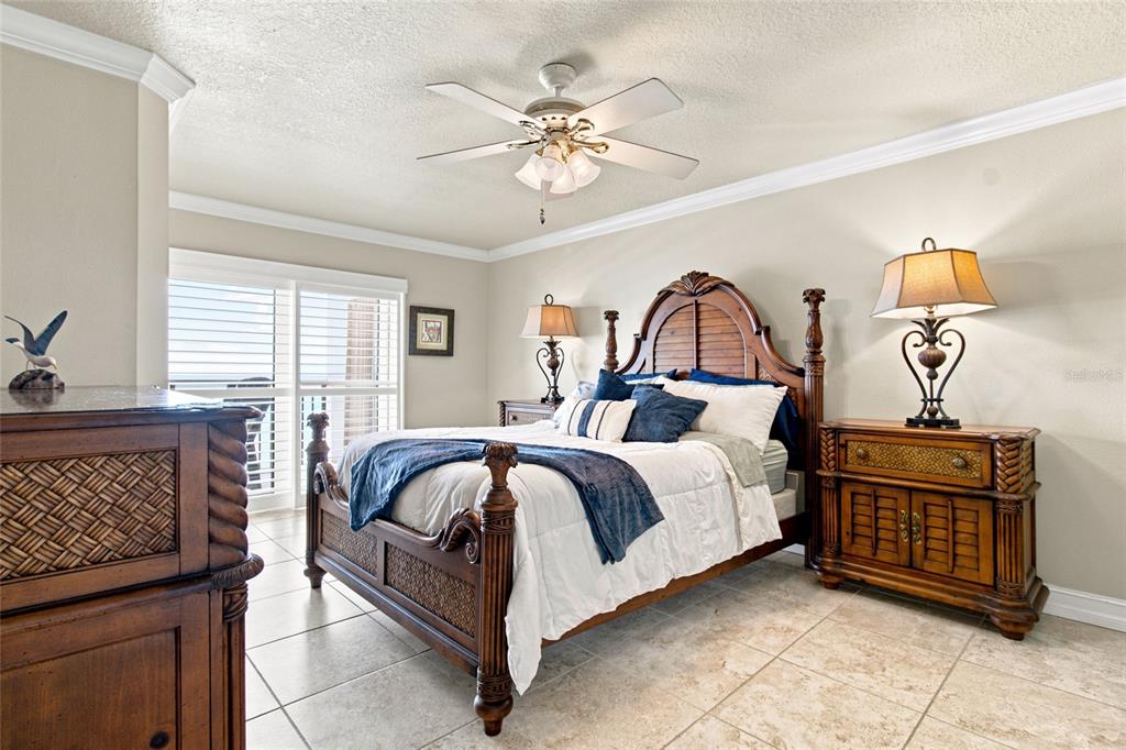 A bedroom features a wooden bed frame, tile flooring, and a ceiling fan — 1270 GULF BOULEVARD UNIT 2007, CLEARWATER BEACH, FL