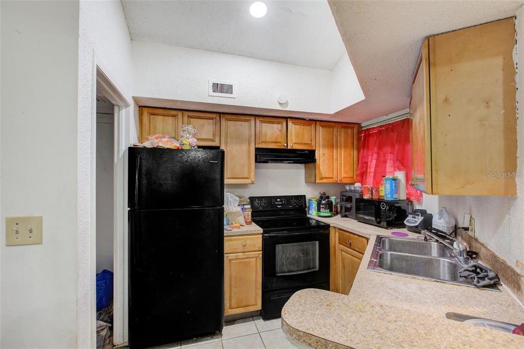 A kitchen features wood cabinets, black appliances, a double sink, and a vaulted ceiling — 1956 LAKE ATRIUMS CIRCLE UNIT 141, ORLANDO, FL