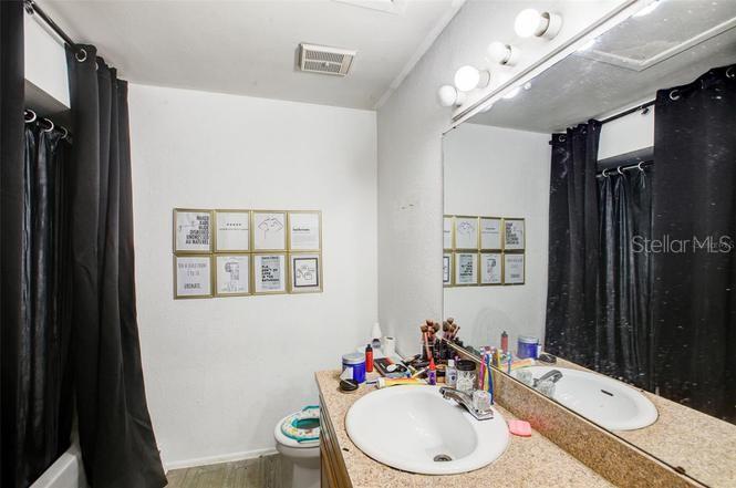 A bathroom features a vanity with a beige countertop, a large mirror, and black curtains — 1956 LAKE ATRIUMS CIRCLE UNIT 141, ORLANDO, FL