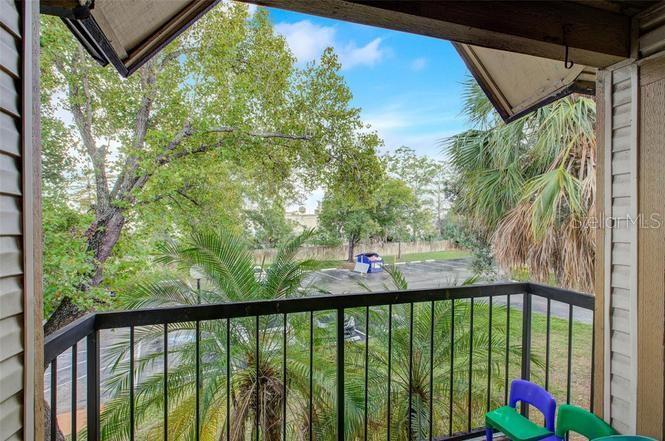 A balcony view overlooking a parking lot with palm trees and a blue dumpster — 1956 LAKE ATRIUMS CIRCLE UNIT 141, ORLANDO, FL