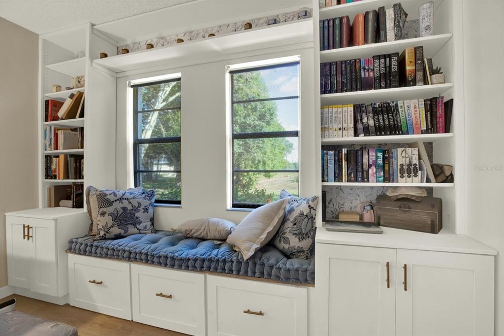 A built-in window seat with storage drawers sits between two white floor-to-ceiling bookshelves — 10800 US HIGHWAY 19 N UNIT 136, PINELLAS PARK, FL