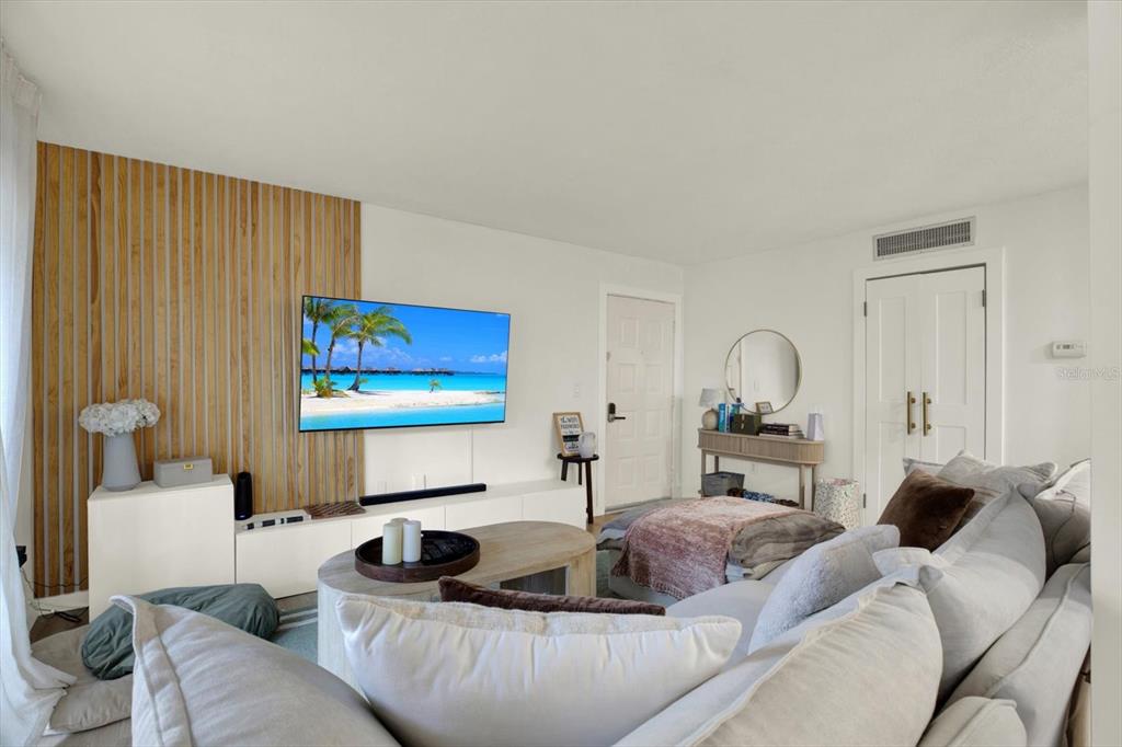 A living room features a wood-slat accent wall, a wall-mounted television, and a sectional sofa — 10800 US HIGHWAY 19 N UNIT 136, PINELLAS PARK, FL