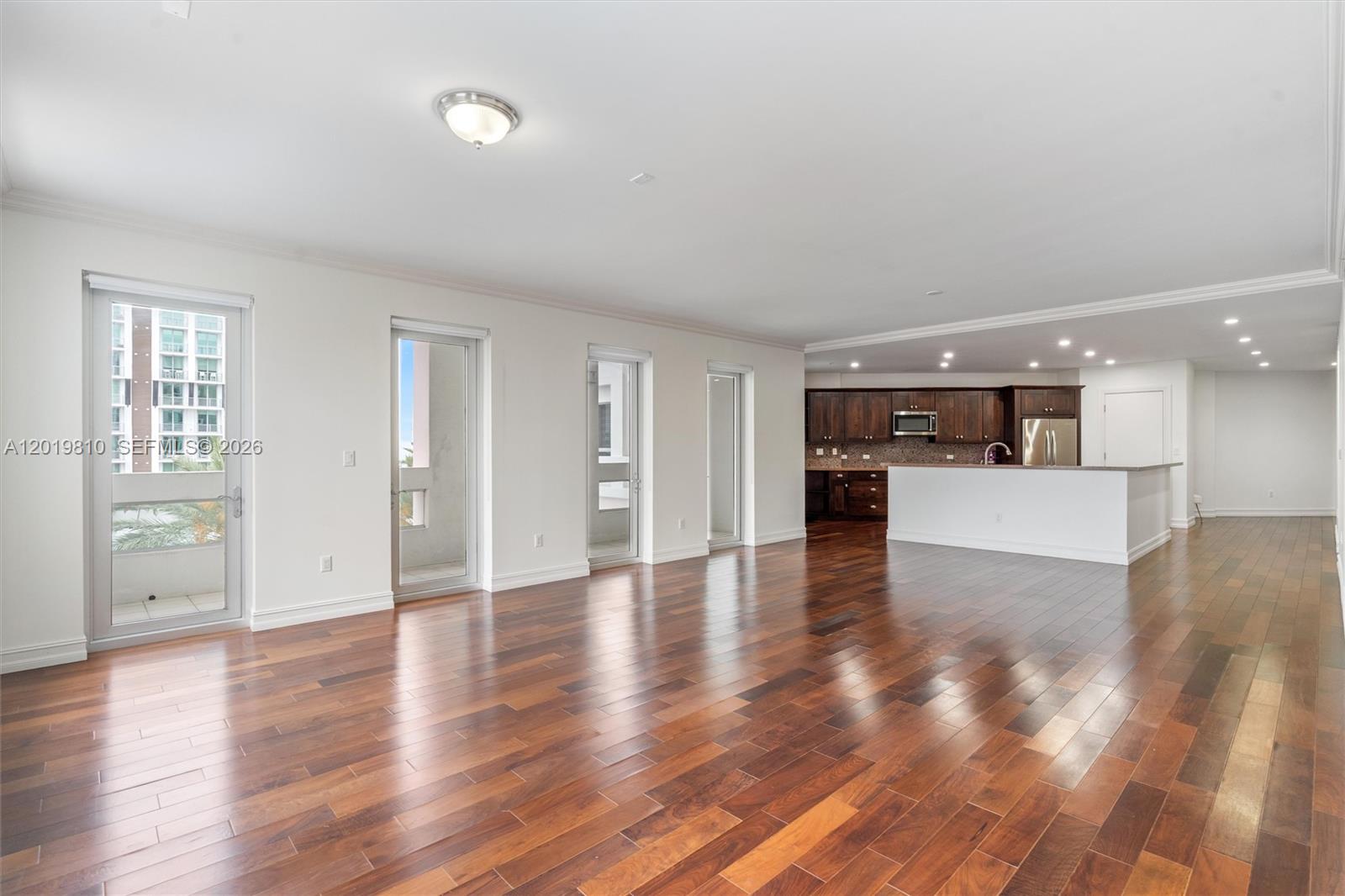An open-concept living area features dark hardwood floors, white walls, and a kitchen with dark cabinetry — 455 E Palmetto Park Rd # 4E, Boca Raton FL 33432, BOCA RATON, FL
