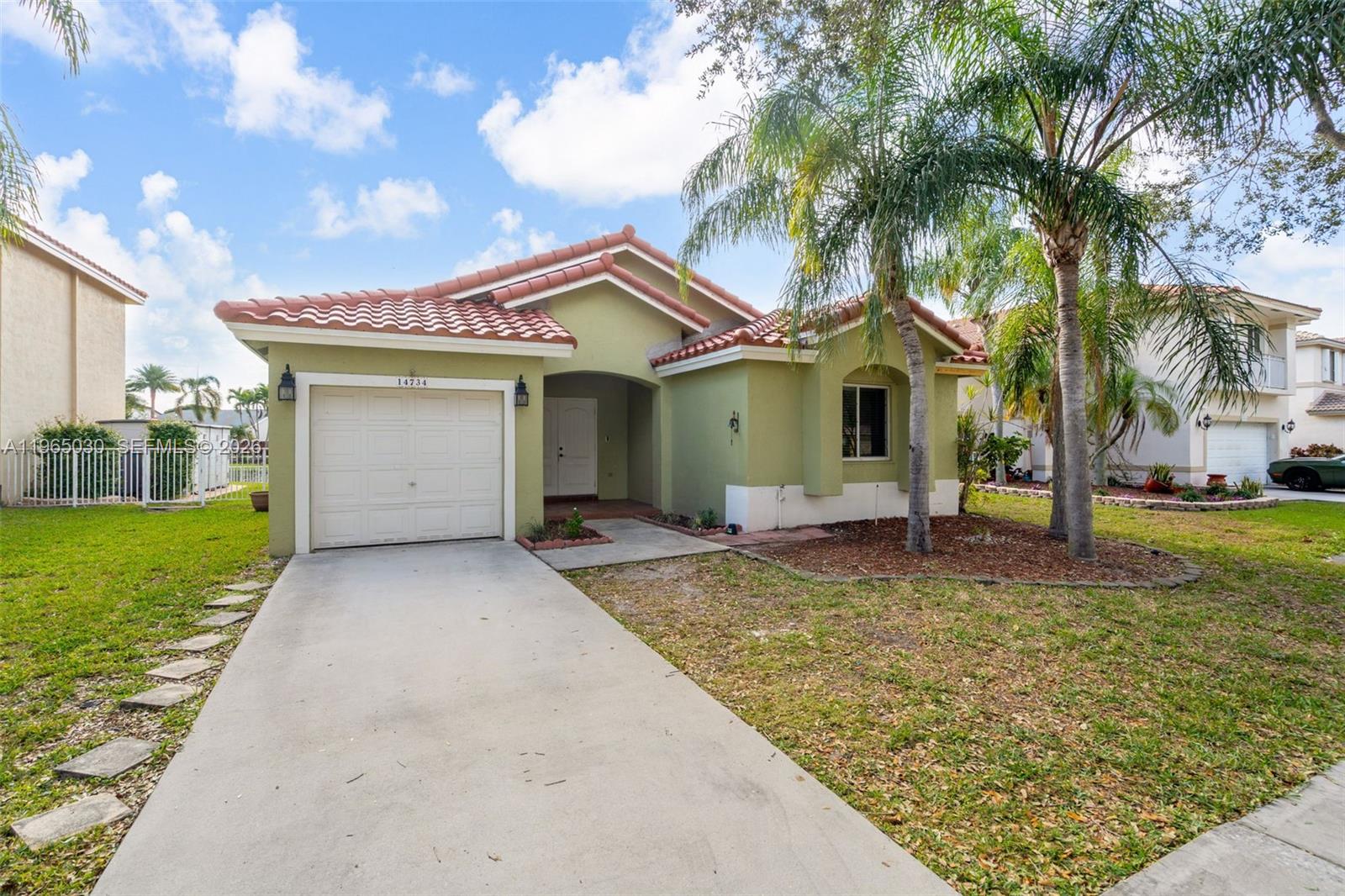A single-story house with a green exterior, a tiled roof, and a concrete driveway — 14734 Via Tivoli Ct, Davie FL 33325, DAVIE, FL