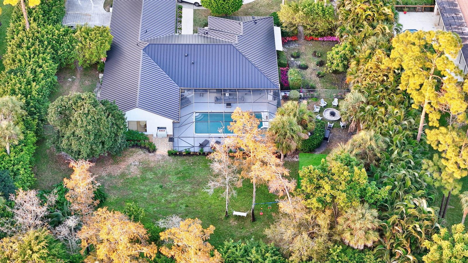An aerial view shows a house with a dark metal roof and a screened-in pool — 13302 Doubletree Circle, Wellington FL 33414, WELLINGTON, FL