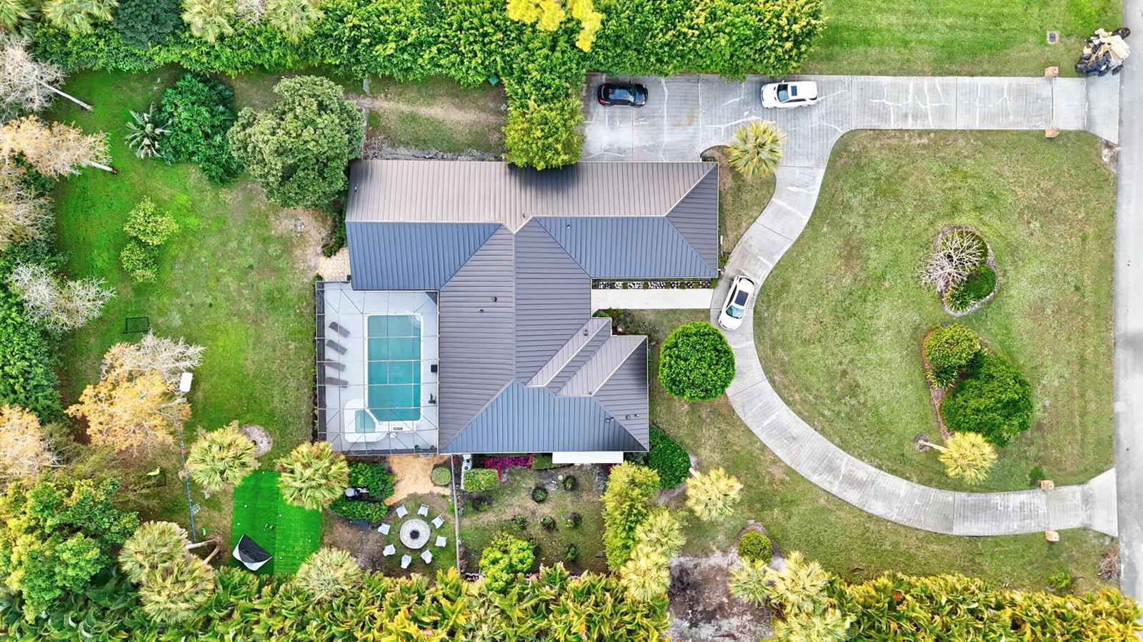 An aerial view shows a house with a metal roof, pool, and curved driveway — 13302 Doubletree Circle, Wellington FL 33414, WELLINGTON, FL
