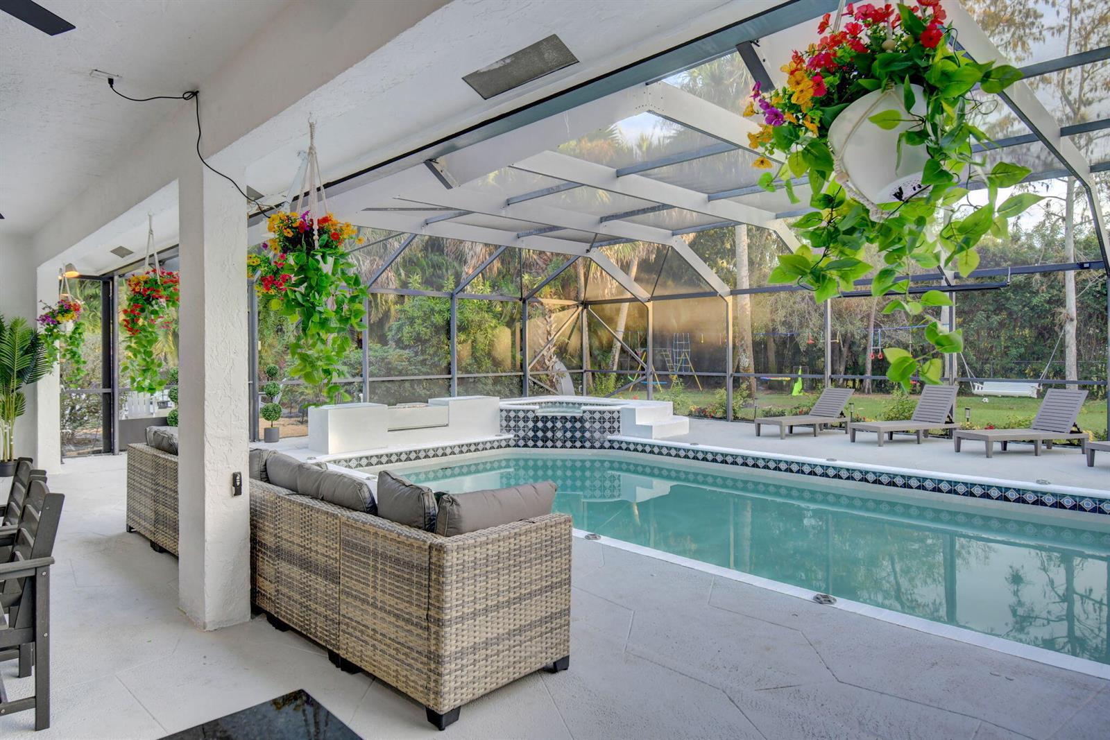A covered patio features a swimming pool, a hot tub, and outdoor furniture — 13302 Doubletree Circle, Wellington FL 33414, WELLINGTON, FL