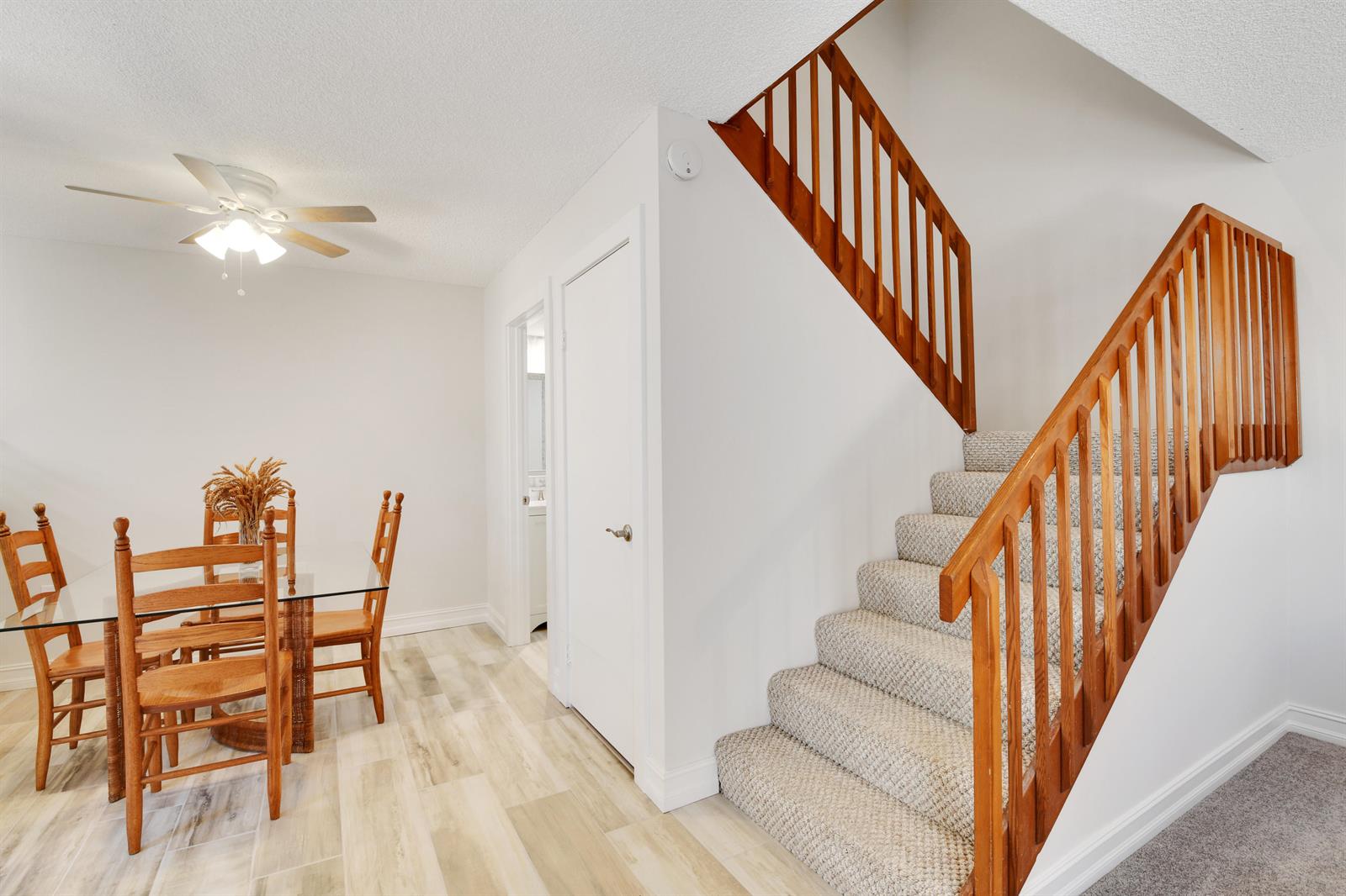 A dining area with a glass table and wooden chairs sits beside a carpeted staircase — 1603 16th Court, Jupiter FL 33477, JUPITER, FL