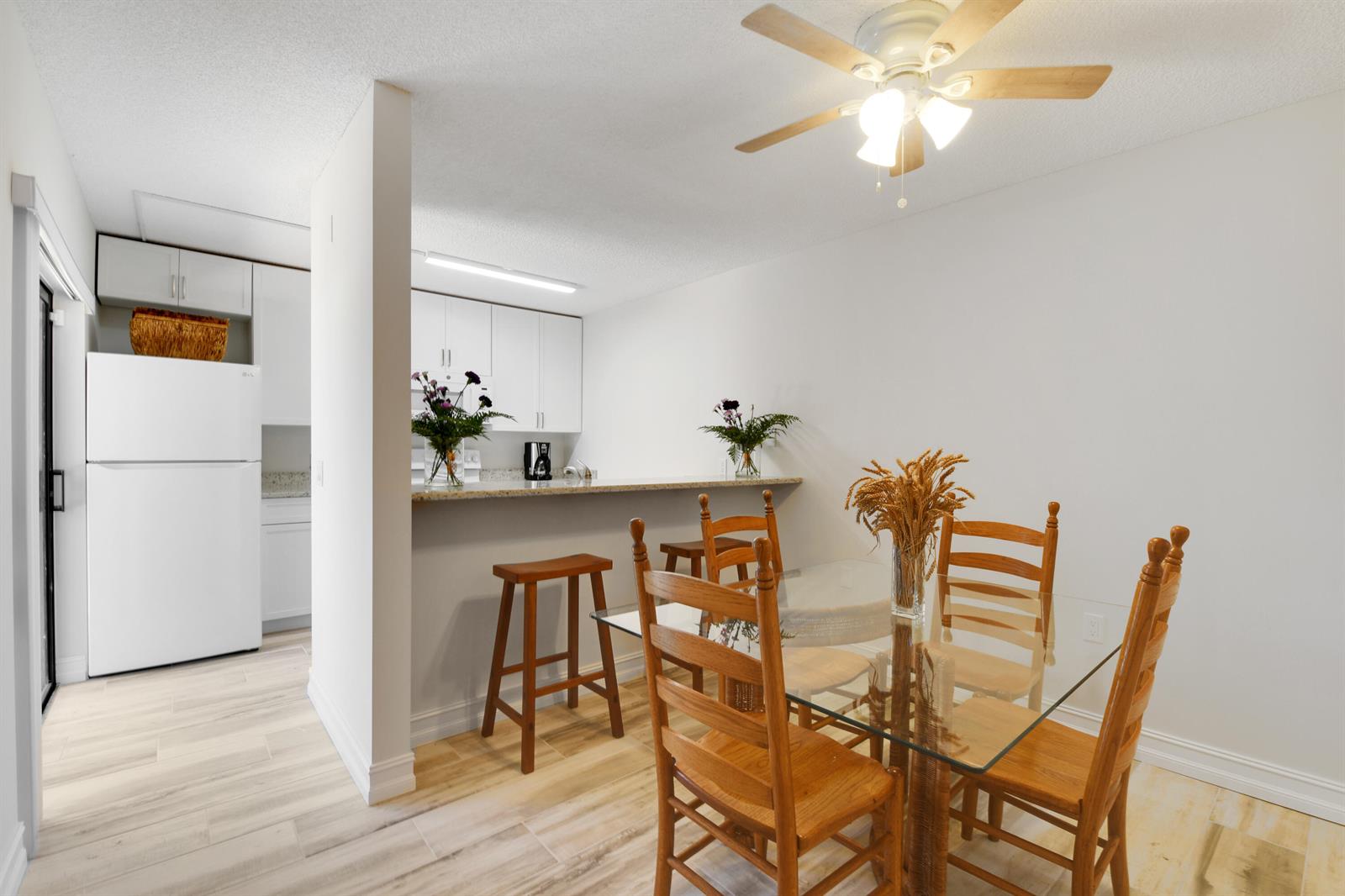 A dining area with a glass table and wooden chairs sits beside a kitchen counter — 1603 16th Court, Jupiter FL 33477, JUPITER, FL