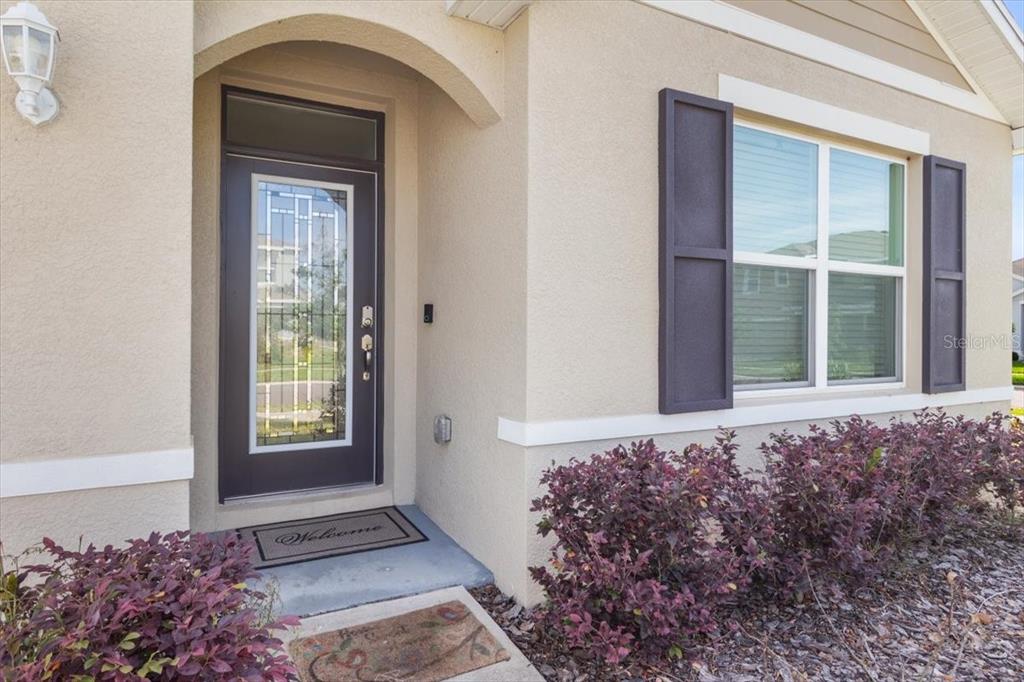 The exterior front entrance features a dark door with glass panels and a welcome mat — 35830 ELLSWORTH PLACE, ZEPHYRHILLS, FL