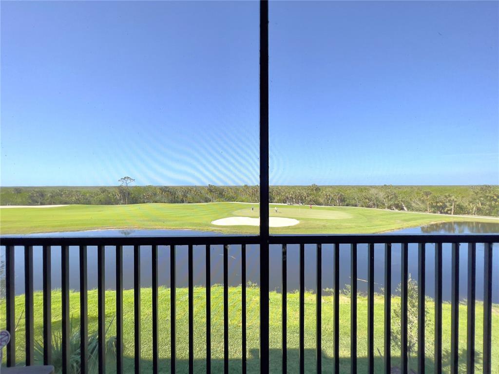 A view of a golf course and pond from a screened-in balcony — 14051 HERITAGE LANDING BOULEVARD UNIT 537, PUNTA GORDA, FL
