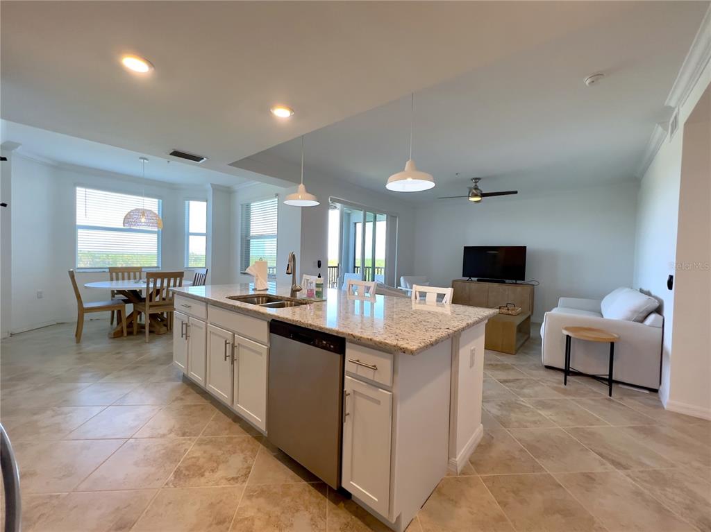 An open-concept kitchen with a granite island and white cabinets overlooks a living area — 14051 HERITAGE LANDING BOULEVARD UNIT 537, PUNTA GORDA, FL