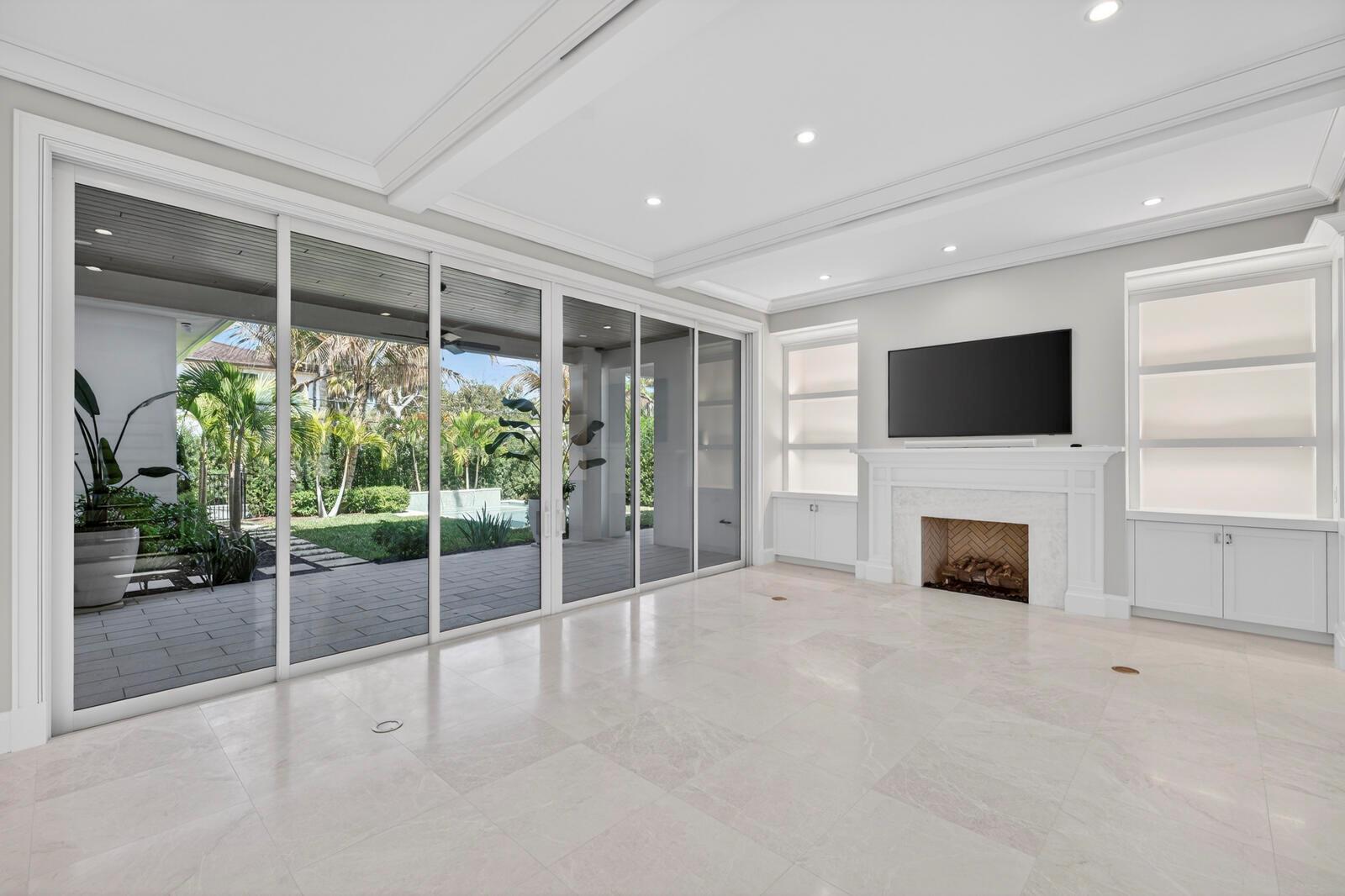 A bright living room features a fireplace, built-in shelving, and large sliding glass doors — VERO BEACH, FL