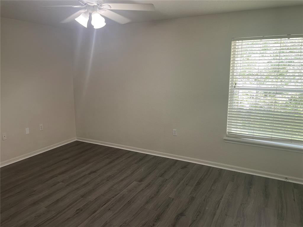 An empty bedroom features light gray walls, a ceiling fan, and wood-look vinyl flooring — 6233 ASHBURY PALMS DRIVE, TAMPA, FL