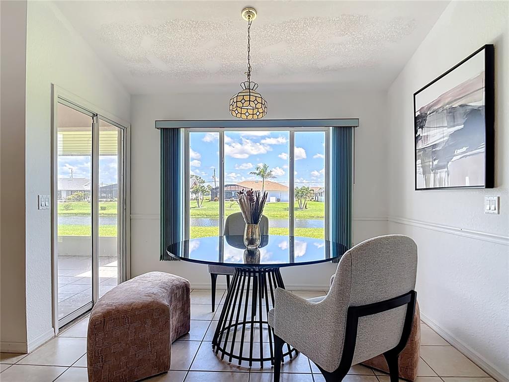 A dining area features a glass-topped table, upholstered chairs, a pendant light, and sliding doors — 104 MARK TWAIN LANE, ROTONDA WEST, FL