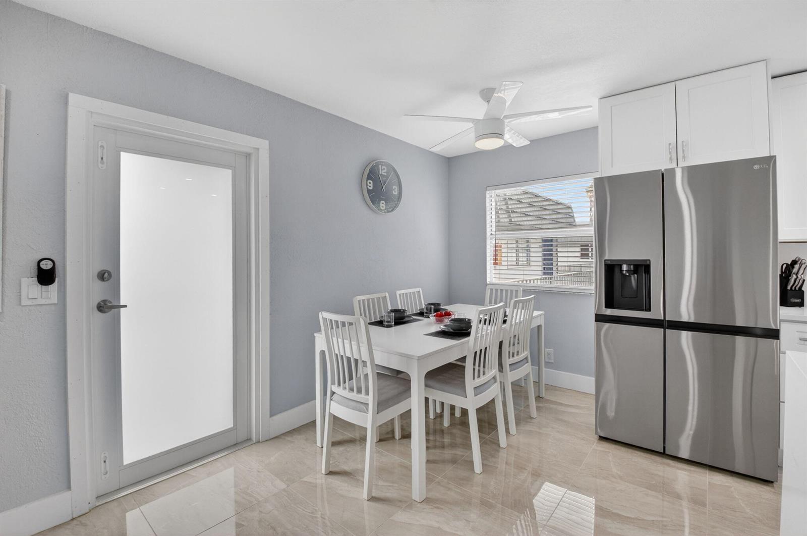 A dining area features a white table with six chairs, a stainless refrigerator, and tile flooring — 321 Saxony Trail # G, Delray Beach FL 33446, DELRAY BEACH, FL