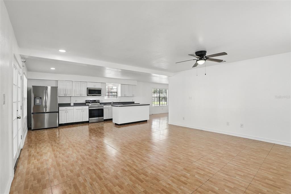 An open-concept kitchen and living area features white cabinetry, stainless steel appliances, and wood-look flooring — 820 ALTALOMA AVENUE, ORLANDO, FL