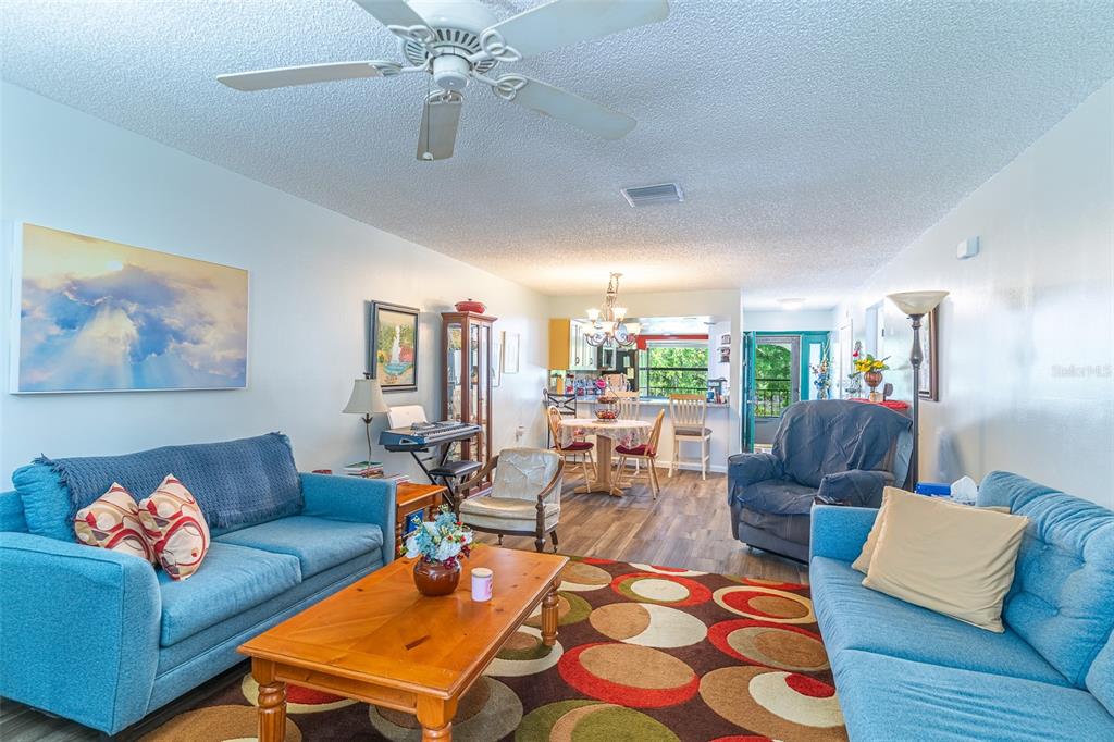 A living room with two blue sofas, a wooden coffee table, and a dining area — 3007 GRANADA COURT UNIT 4, LAKE WALES, FL