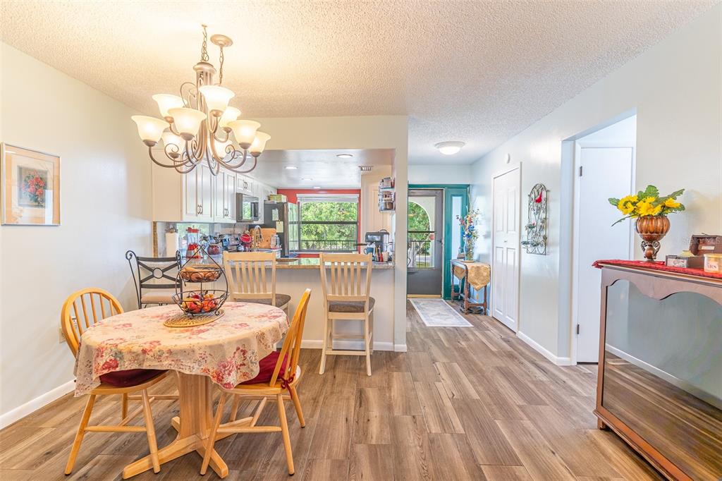 A dining area with a floral tablecloth, chandelier, and breakfast bar overlooking a kitchen — 3007 GRANADA COURT UNIT 4, LAKE WALES, FL