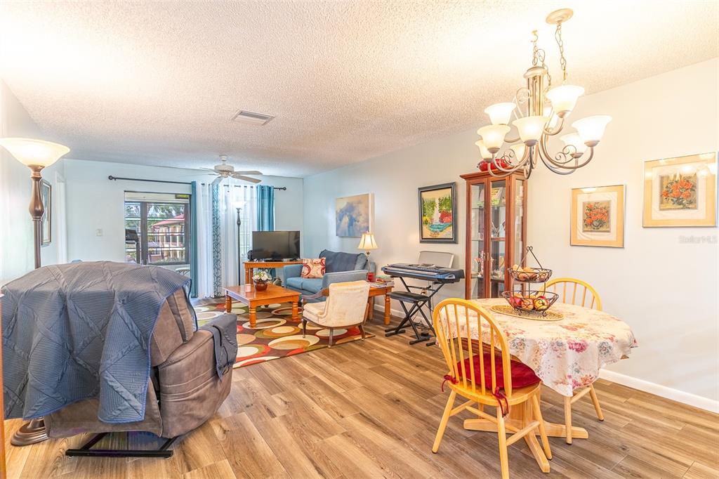 A living and dining area with wood-look flooring, a chandelier, and a covered recliner — 3007 GRANADA COURT UNIT 4, LAKE WALES, FL