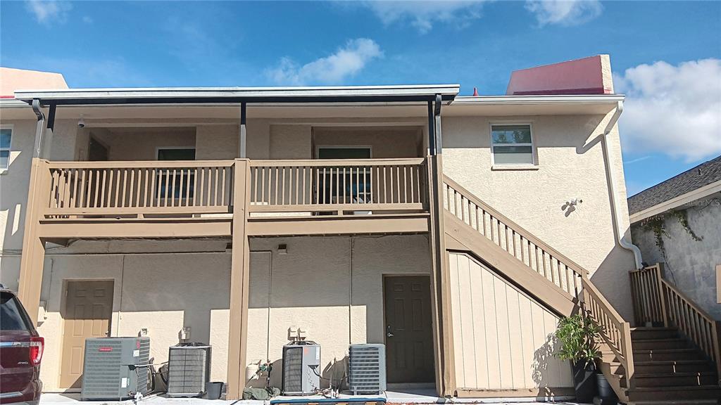 The exterior of a two-story building features a wooden balcony, an outdoor staircase, and HVAC units — 14506 S TAMIAMI TRAIL UNIT D, NORTH PORT, FL