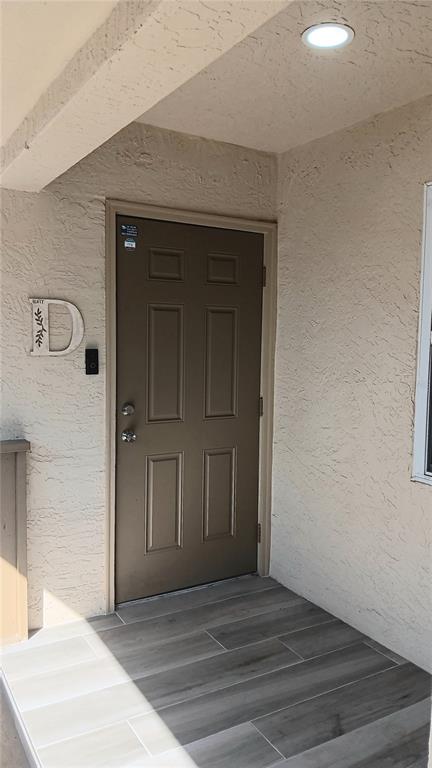 A brown front door with a letter D sign and gray wood-look tile flooring — 14506 S TAMIAMI TRAIL UNIT D, NORTH PORT, FL