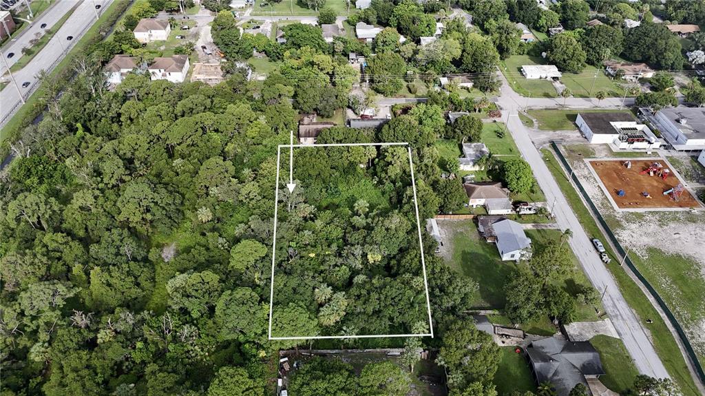 An aerial view shows a rectangular, wooded vacant lot outlined in white — TENNESSEE AVENUE, FORT PIERCE, FL