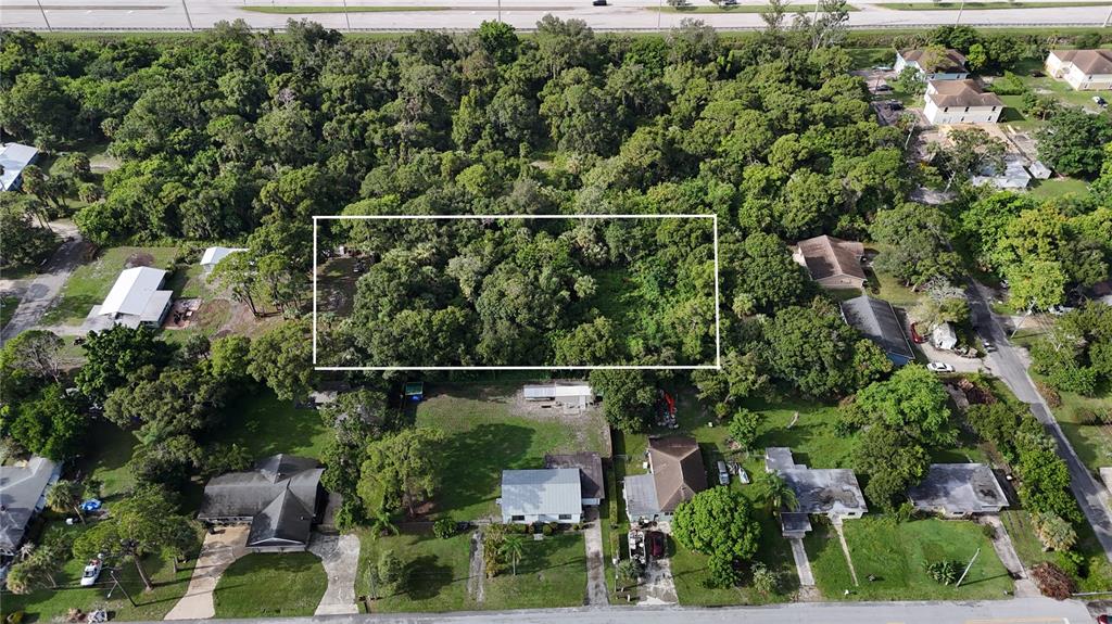 An aerial view shows a rectangular, tree-covered vacant lot outlined in white among residential houses — TENNESSEE AVENUE, FORT PIERCE, FL