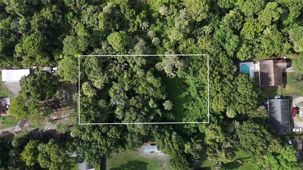 An aerial view shows a rectangular lot outlined in white amidst a dense wooded area — TENNESSEE AVENUE, FORT PIERCE, FL