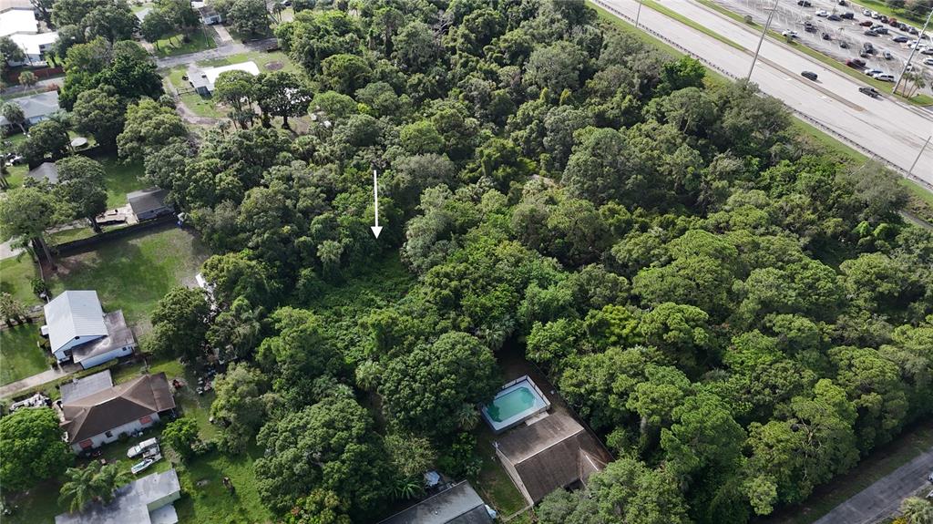 An aerial view shows a wooded residential lot with a white arrow pointing toward vegetation — TENNESSEE AVENUE, FORT PIERCE, FL
