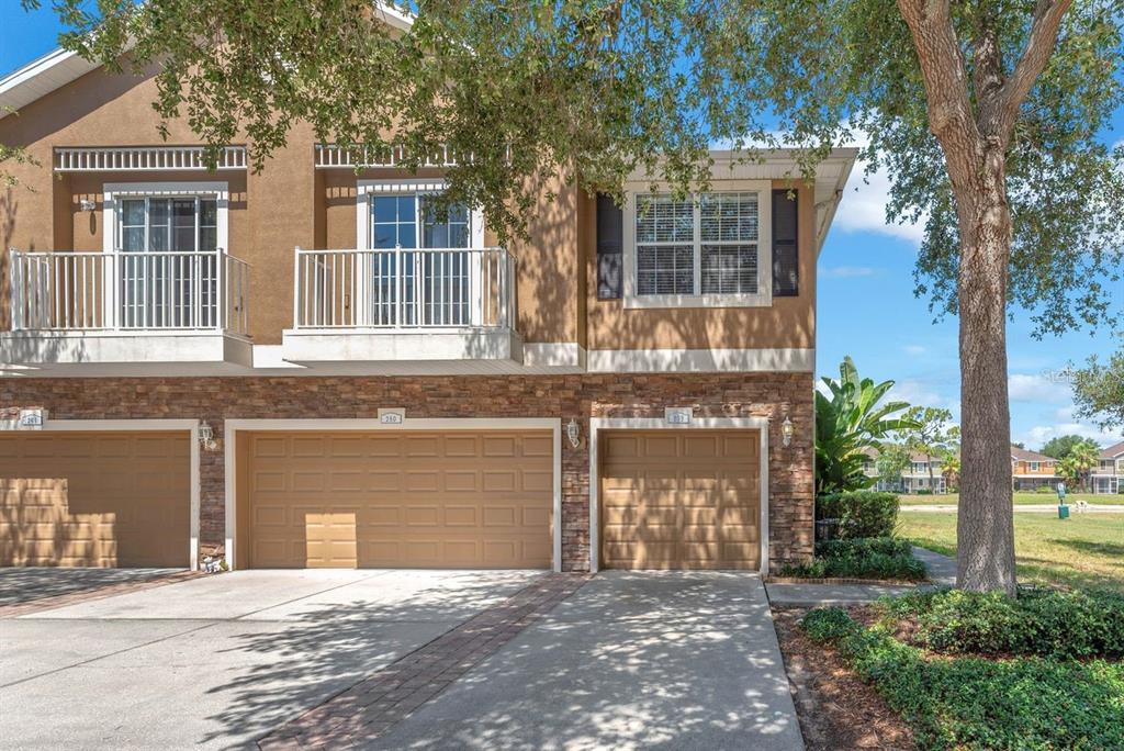 A two-story townhouse exterior features tan stucco, stone veneer, two garage doors, and upper balconies — 7001 INTERBAY BOULEVARD UNIT 259, TAMPA, FL