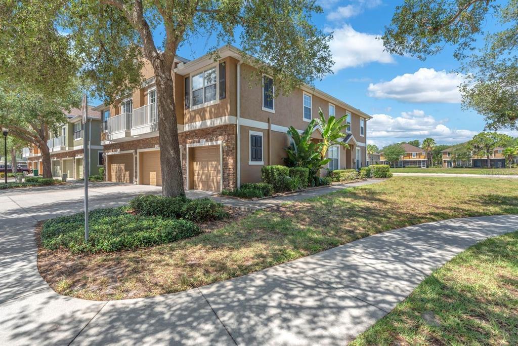 A two-story tan townhouse with a stone facade, attached garages, and a paved walkway — 7001 INTERBAY BOULEVARD UNIT 259, TAMPA, FL