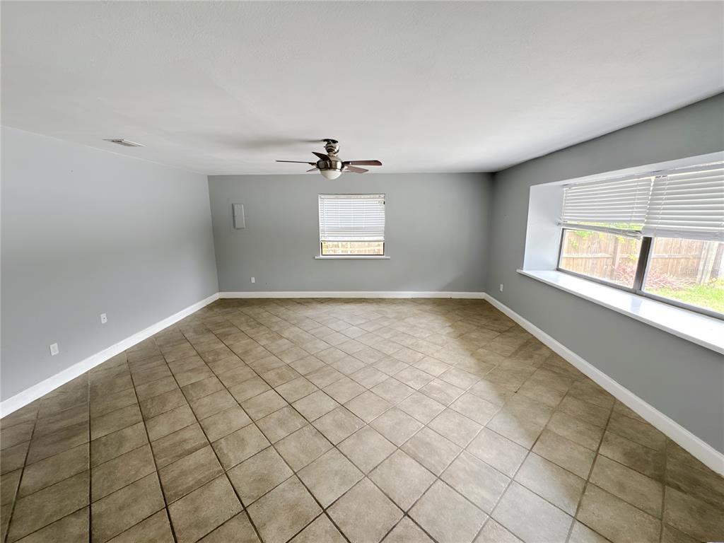 An empty room features gray walls, diagonal floor tiles, a ceiling fan, and two windows — 4710 HOXIE LANE, SARASOTA, FL