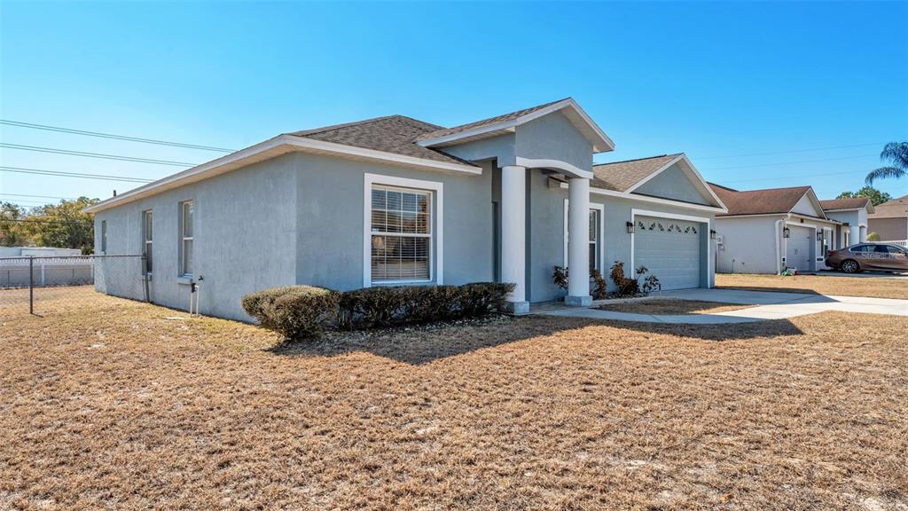 A single-story light blue house with a two-car garage and a front porch with columns — 6146 MISSION DRIVE, LAKELAND, FL