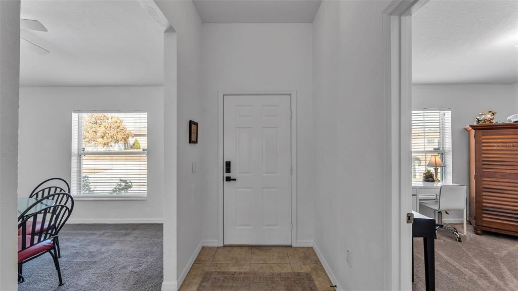 A white front door opens into a tiled entryway flanked by a dining area and office — 6146 MISSION DRIVE, LAKELAND, FL