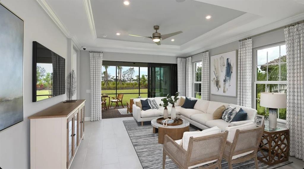 A living room features a white sectional sofa, two wooden chairs, and a sliding glass door — 3225 TORTA COURT, BRADENTON, FL