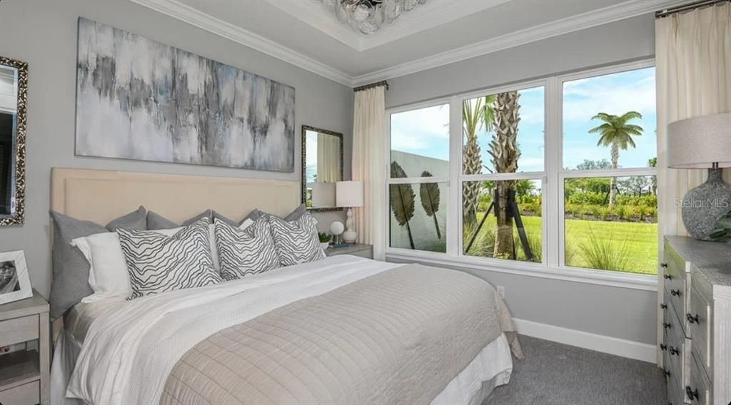 A bedroom features a bed with patterned pillows, a large abstract painting, and floor-to-ceiling windows — 3225 TORTA COURT, BRADENTON, FL