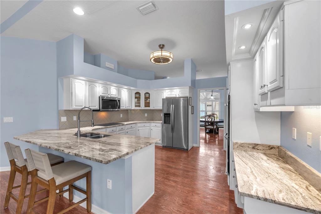 A kitchen with white cabinets, granite countertops, stainless steel appliances, and a breakfast bar — 4419 SWIFT CIRCLE, VALRICO, FL