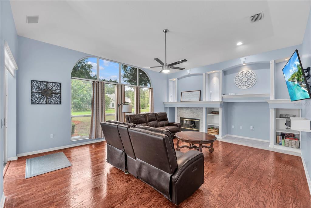A living room features hardwood floors, a fireplace, built-in shelving, and large arched windows — 4419 SWIFT CIRCLE, VALRICO, FL
