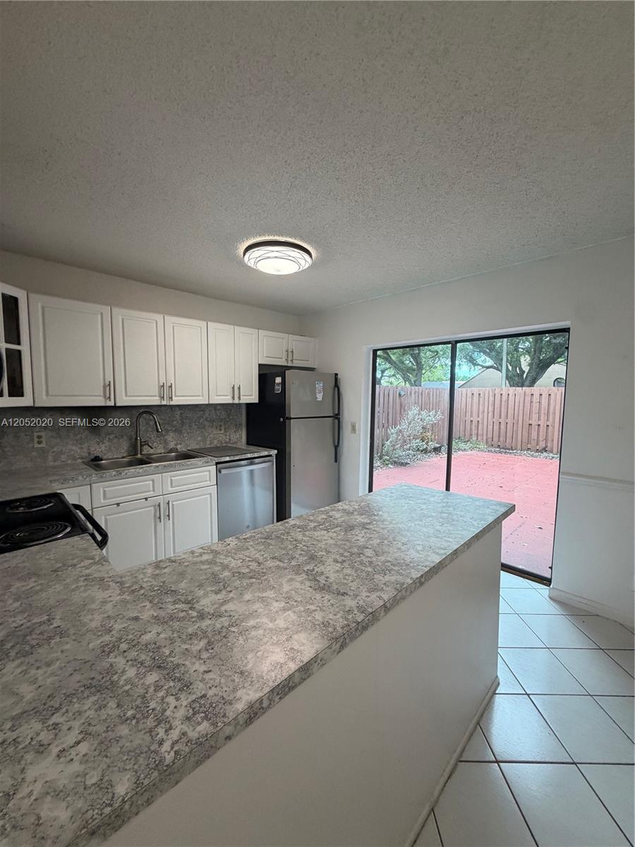 A kitchen features white cabinets, gray laminate countertops, stainless steel appliances, and a sliding door — 2563 CAMELOT # 2563, Cooper City FL 33026, COOPER CITY, FL